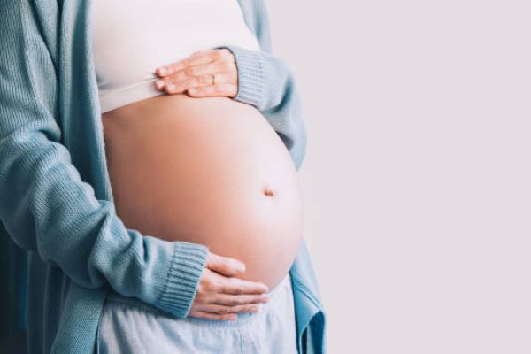 istockphoto-1835179103-612×612 Beautiful pregnant woman holds hands on her belly. Happy mother waiting for baby birth. Pregnancy, maternity, preparation and expectation concept.